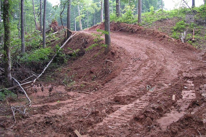 Cleared and graded route through a wooded slope for a sewer line