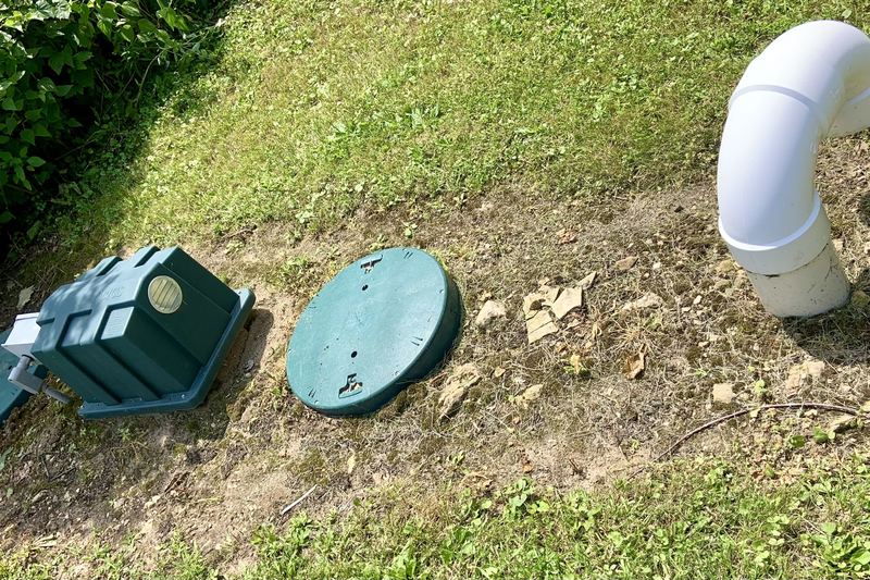 Green septic tank access lids and vent pipe in a lawn